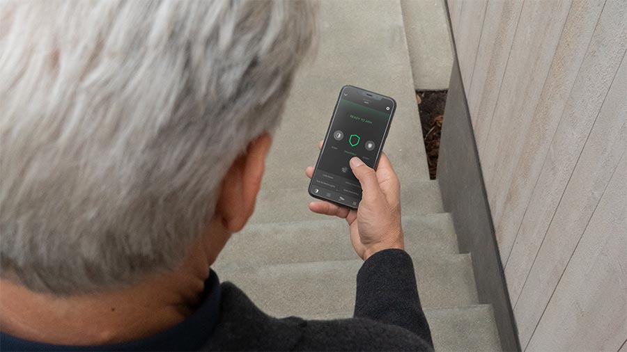 Person checking home security status on a smartphone near an entryway