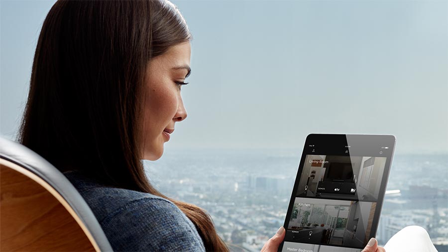 Woman holding a tablet viewing home camera feeds with a city view